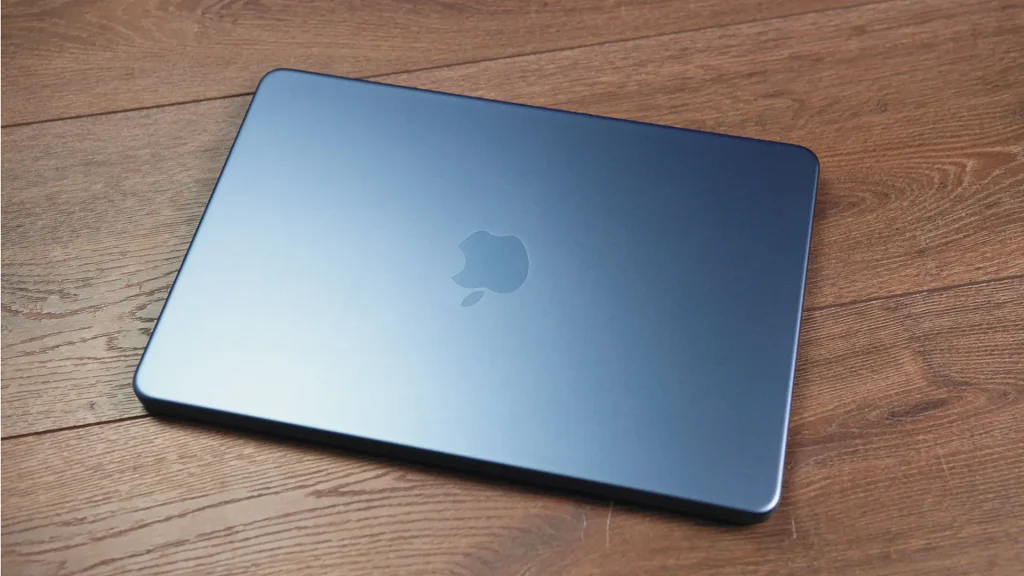 Blue laptop closed on a wooden surface, with the Apple logo visible on the lid