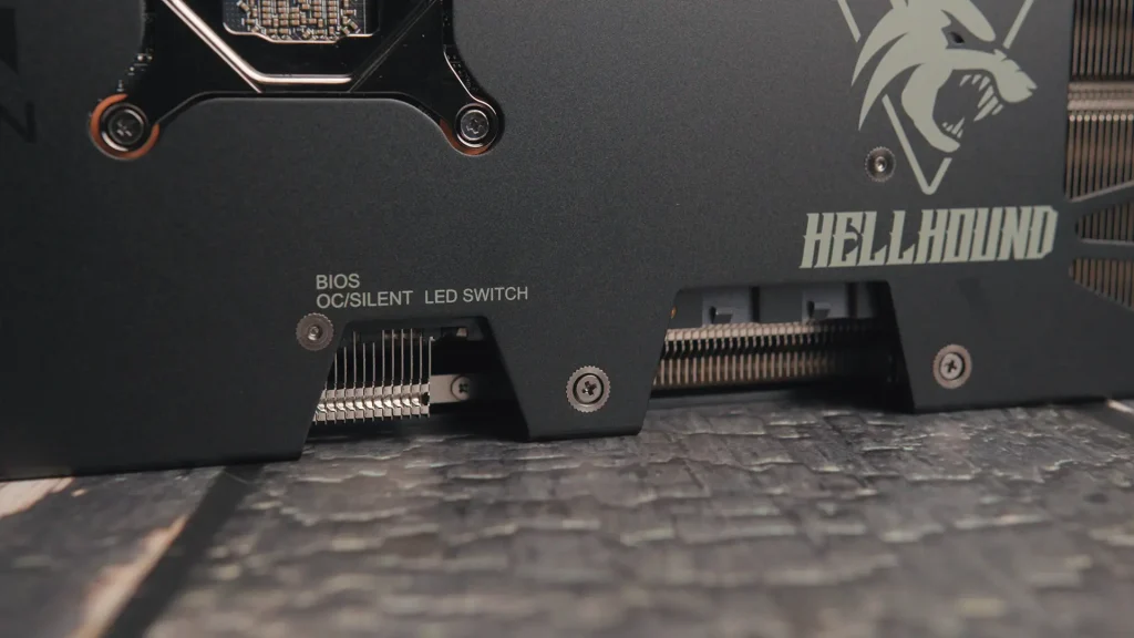 Close-up of a dark graphics card with the 'HELLHOUND' branding and the BIOS OC/Silent LED switch visible at the lower left.