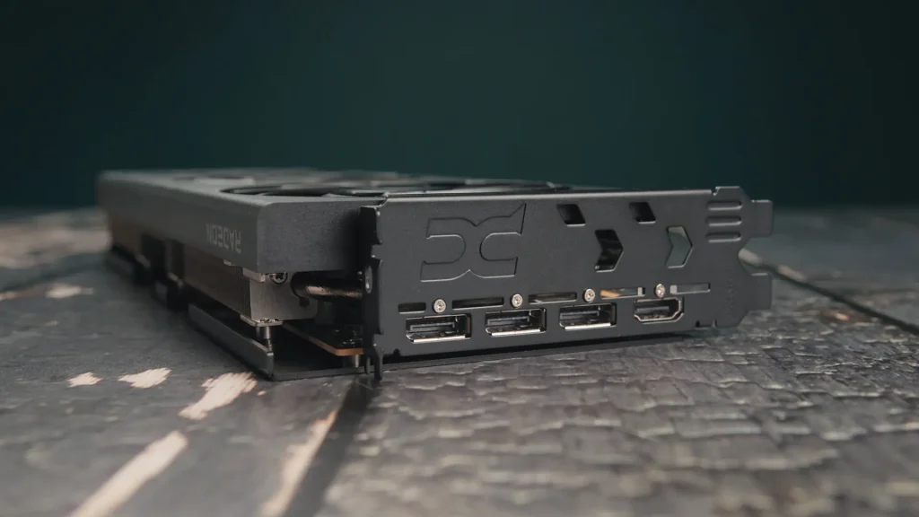 Black graphics card resting on a wooden surface, displaying its edge with multiple video ports visible